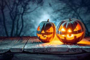 2 carved pumpkins lit up for Halloween with a woodland scene in the background